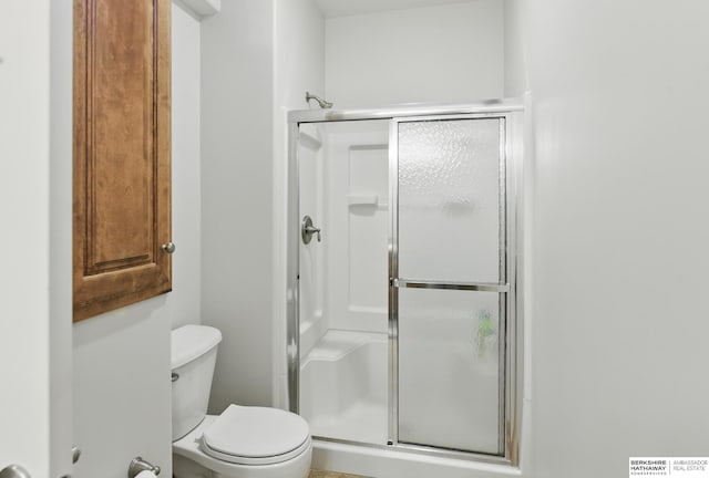bathroom featuring a shower stall and toilet