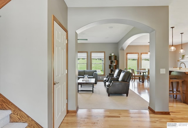 living room with light wood-style flooring, arched walkways, baseboards, and ceiling fan
