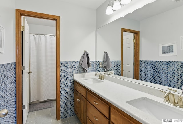 bathroom featuring tile walls, wainscoting, double vanity, and tile patterned flooring
