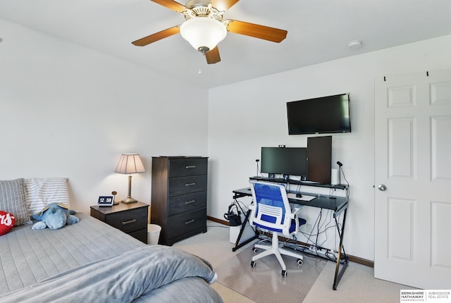 bedroom featuring light colored carpet, a desk, baseboards, and a ceiling fan
