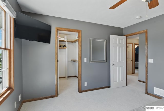 unfurnished bedroom featuring carpet floors, a walk in closet, baseboards, and a closet