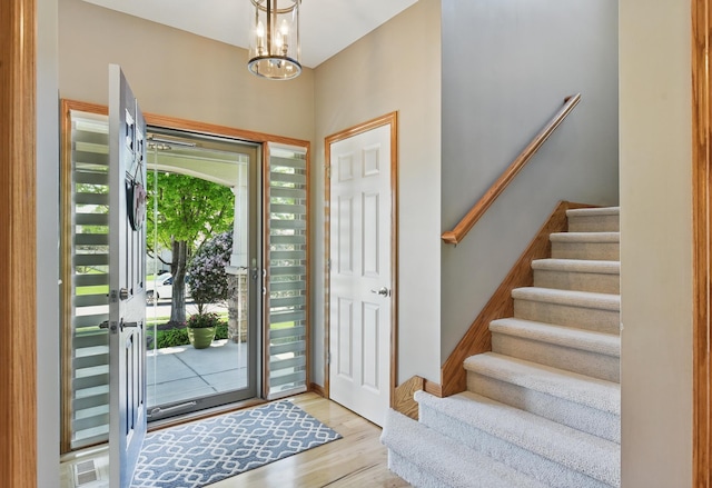 entryway with stairway, wood finished floors, and a chandelier