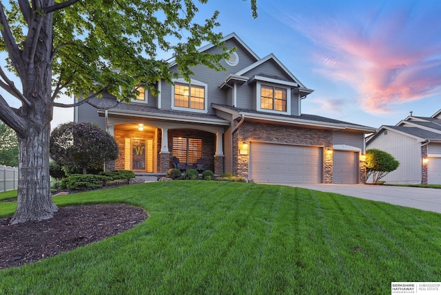 view of front facade featuring driveway, stone siding, a yard, and an attached garage
