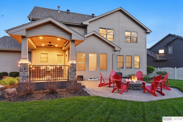 back of property featuring a fire pit, a patio area, roof with shingles, and stone siding