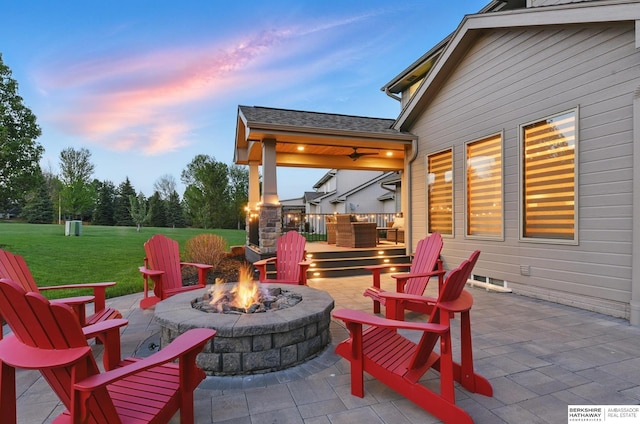 patio terrace at dusk with a fire pit and a lawn