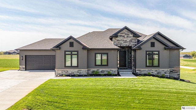view of front of home featuring stone siding, an attached garage, concrete driveway, and a front yard