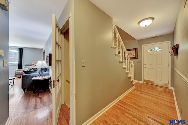 hallway featuring light wood-type flooring, stairs, and baseboards