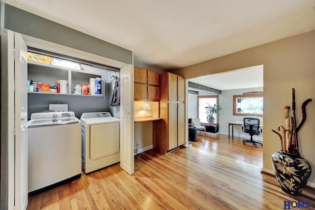 washroom with washing machine and dryer, light wood-style flooring, a desk, and baseboards
