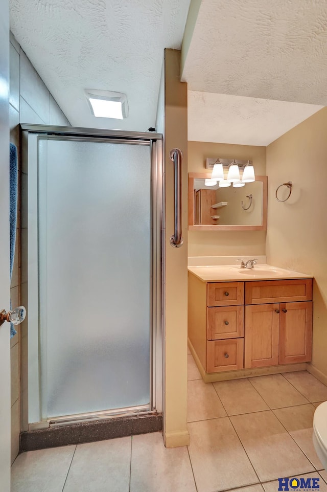 full bath featuring a shower stall, vanity, tile patterned floors, a textured ceiling, and toilet