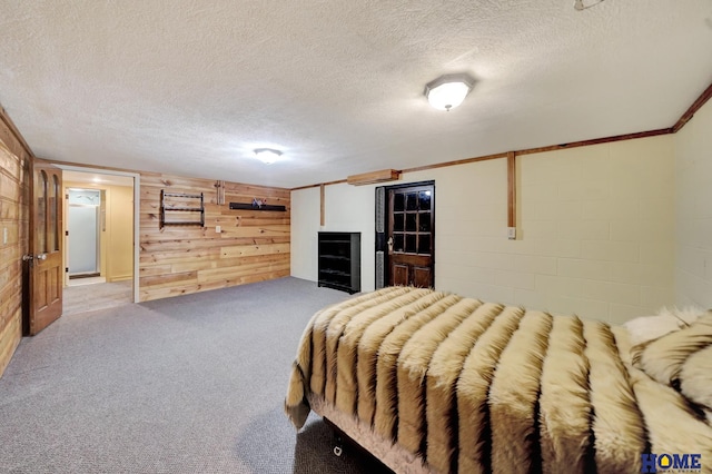 bedroom with wood walls, a textured ceiling, and carpet