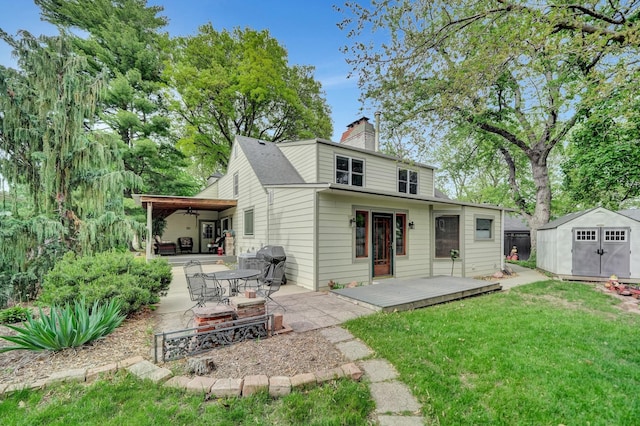 back of property featuring a storage unit, a lawn, a ceiling fan, a patio area, and an outdoor structure