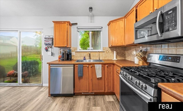 11019 Weber St, Omaha, NE 68142 - kitchen featuring appliances with stainless steel finishes, a sink, light wood-type flooring, backsplash, and a textured ceiling
