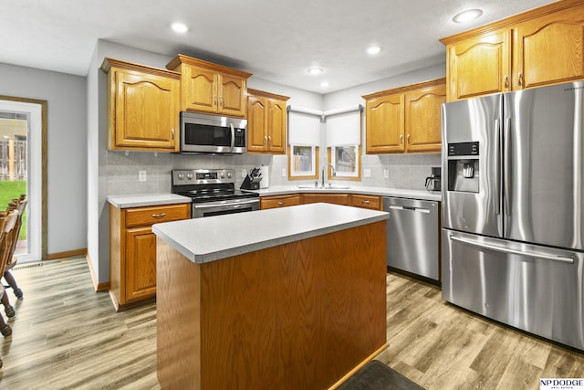 kitchen with stainless steel appliances, a sink, light wood-type flooring, light countertops, and recessed lighting