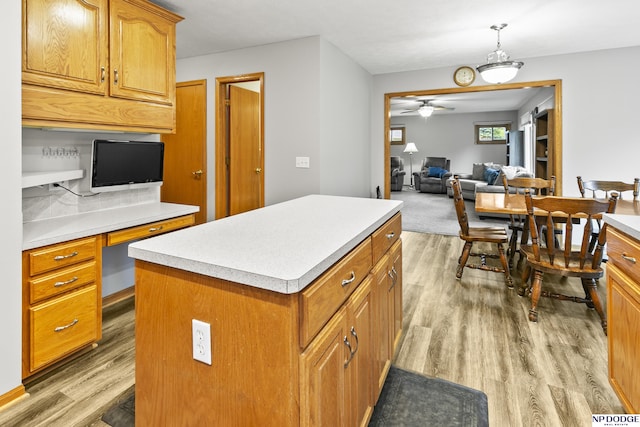 kitchen with light wood finished floors, a center island, light countertops, and open floor plan