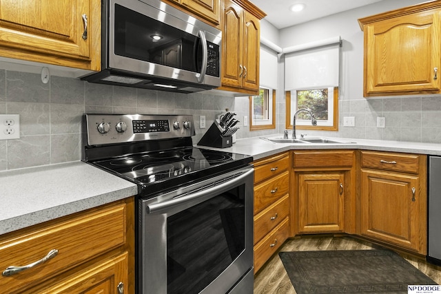 kitchen featuring stainless steel appliances, a sink, light countertops, and brown cabinetry