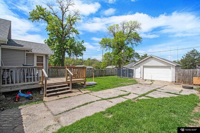 view of yard featuring an outdoor structure, a wooden deck, a detached garage, and a storage shed