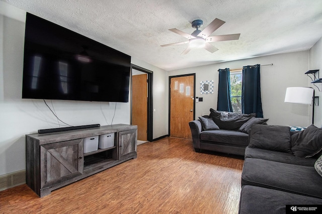 living room featuring a textured ceiling, light wood-style floors, a ceiling fan, and baseboards