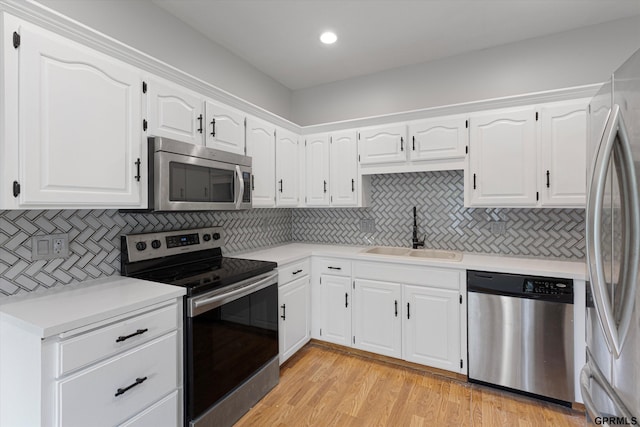 kitchen with appliances with stainless steel finishes, a sink, backsplash, light countertops, and recessed lighting