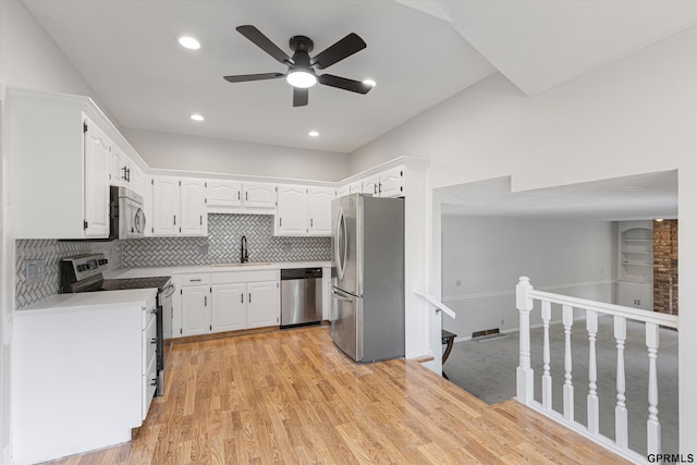 kitchen with stainless steel appliances, a sink, a ceiling fan, white cabinetry, and tasteful backsplash
