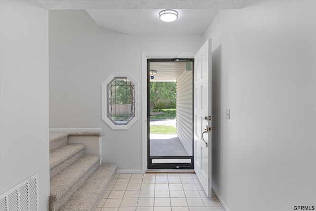 entryway featuring baseboards, light tile patterned floors, and stairway