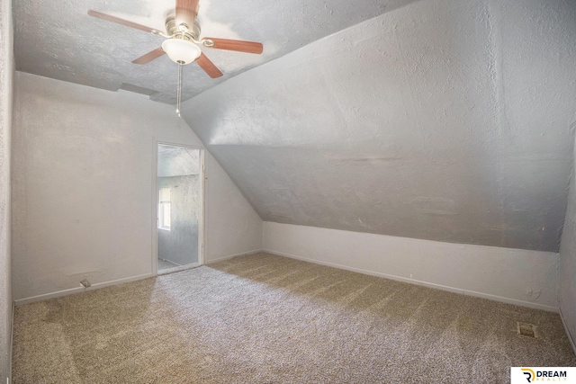 additional living space featuring vaulted ceiling, carpet flooring, a ceiling fan, a textured ceiling, and baseboards
