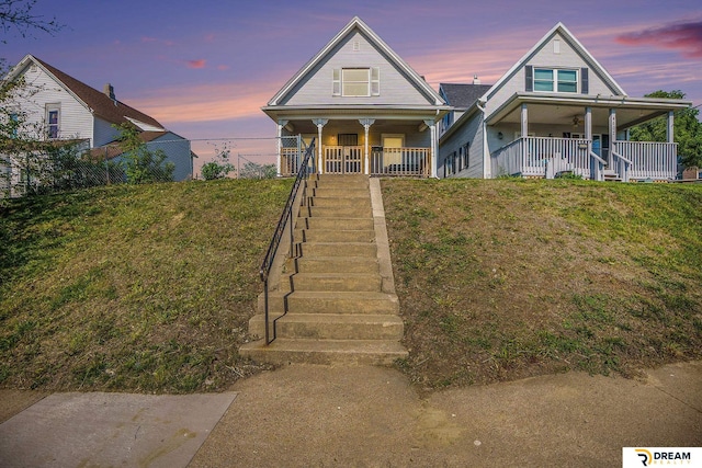 view of front of property featuring a porch, stairway, and a front yard