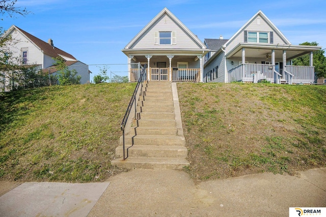 view of front facade featuring covered porch, stairway, and a front lawn