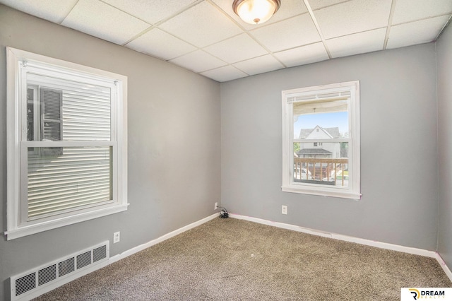 empty room featuring a paneled ceiling, carpet floors, and baseboards