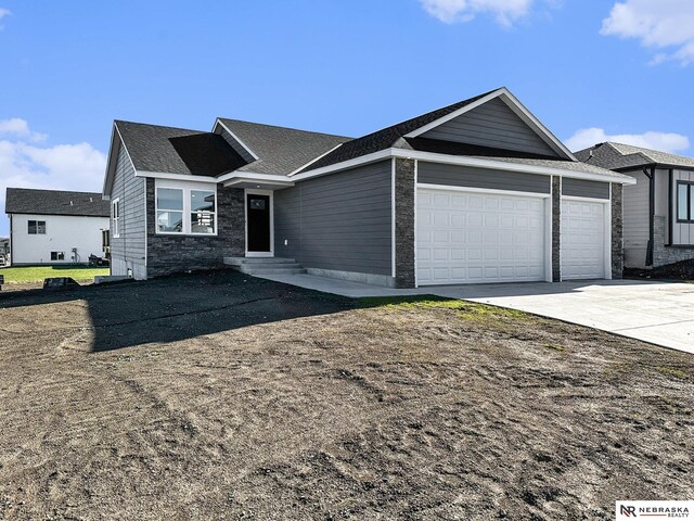 5910 SW 9th St, Lincoln, NE 68523 - ranch-style house featuring an attached garage, concrete driveway, entry steps, stone siding, and a shingled roof