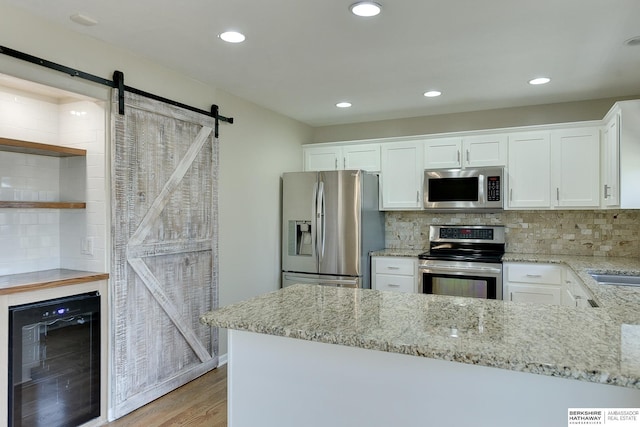 8114 S 167th St, Omaha, NE 68136 - kitchen with appliances with stainless steel finishes, wine cooler, a barn door, white cabinets, and light wood-type flooring