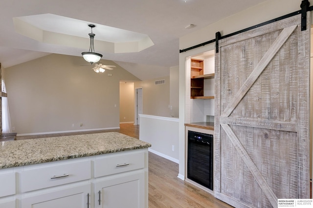8114 S 167th St, Omaha, NE 68136 - kitchen featuring a barn door, beverage cooler, a ceiling fan, white cabinetry, and light wood-style flooring