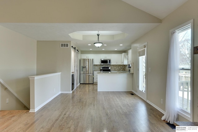 8114 S 167th St, Omaha, NE 68136 - kitchen with stainless steel appliances, a barn door, light wood-style floors, white cabinetry, and tasteful backsplash