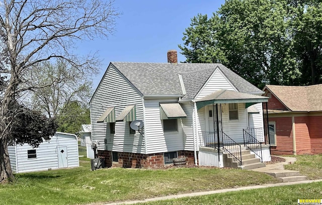 bungalow-style house with a shingled roof, a front lawn, and a chimney