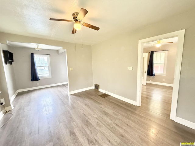 empty room with a ceiling fan, wood finished floors, and baseboards