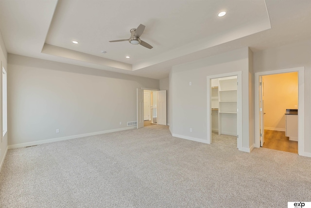 513 13th Ave, Plattsmouth, NE 68048 - unfurnished bedroom with a tray ceiling, light carpet, recessed lighting, baseboards, and a walk in closet