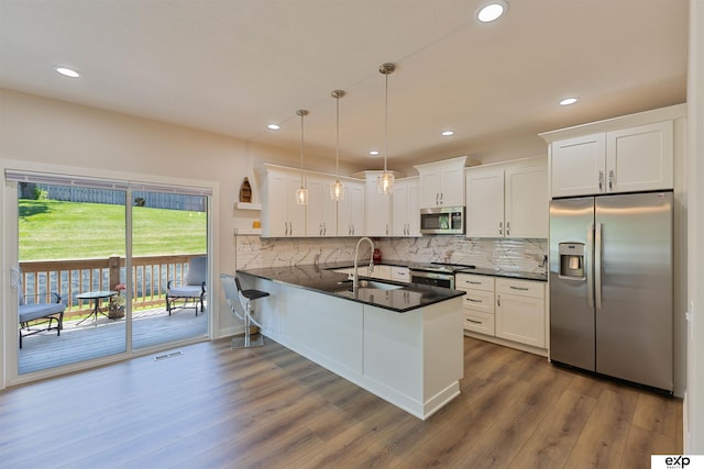 513 13th Ave, Plattsmouth, NE 68048 - kitchen with stainless steel appliances, dark countertops, a peninsula, a sink, and white cabinetry