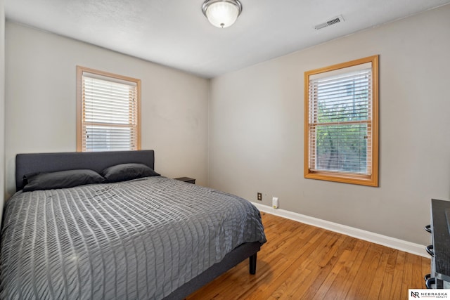 bedroom featuring multiple windows, baseboards, and light wood-style flooring