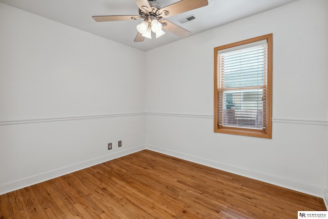 spare room with baseboards, light wood-style floors, and a ceiling fan