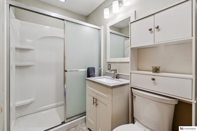 bathroom featuring a shower stall, toilet, and vanity