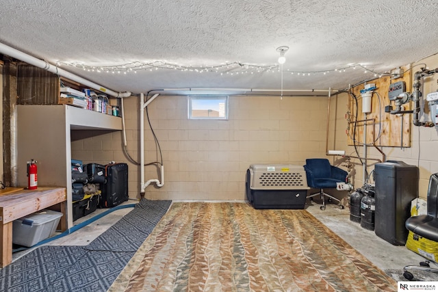 basement with concrete block wall and a textured ceiling