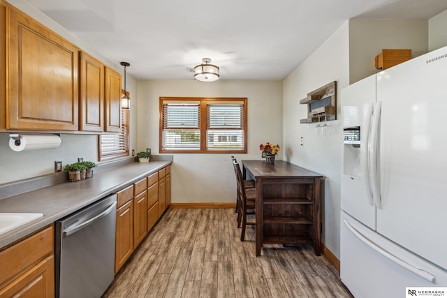 kitchen with white refrigerator with ice dispenser, dishwasher, wood finished floors, baseboards, and brown cabinetry