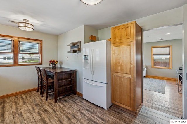 kitchen featuring white refrigerator with ice dispenser, baseboards, wood finished floors, and recessed lighting