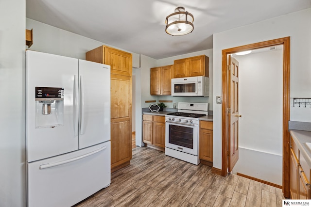 kitchen featuring white appliances, wood finished floors, and brown cabinets