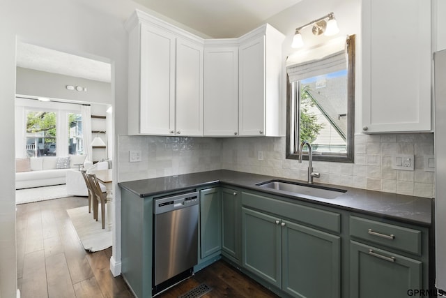 kitchen featuring dishwasher, a sink, dark countertops, and white cabinets
