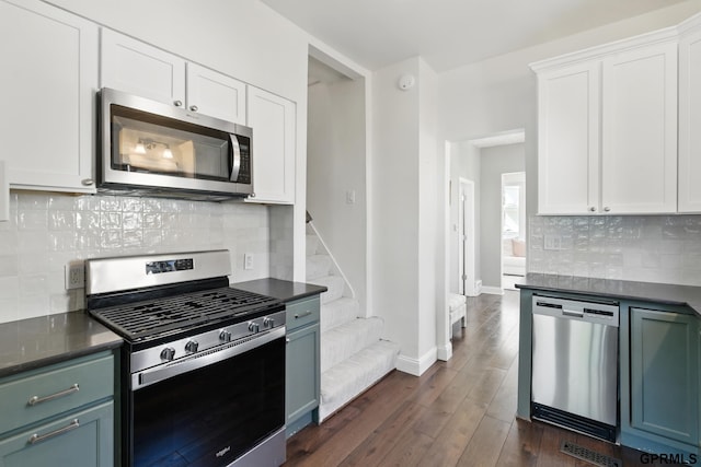 kitchen featuring stainless steel appliances, dark countertops, white cabinetry, and dark wood finished floors