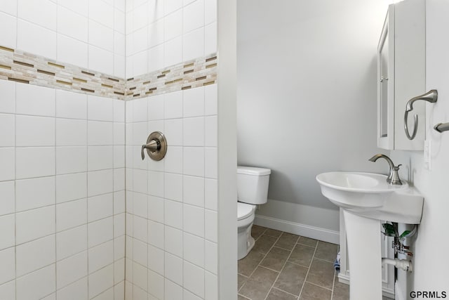 full bath with toilet, a tile shower, baseboards, and tile patterned floors