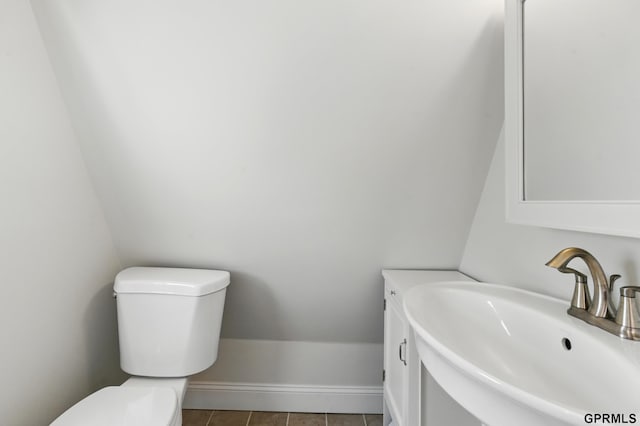 half bath with toilet, tile patterned flooring, and vanity
