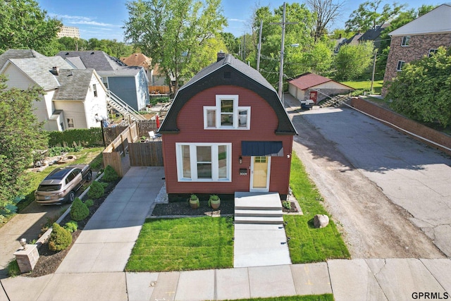 view of front of home featuring a gambrel roof, driveway, and fence