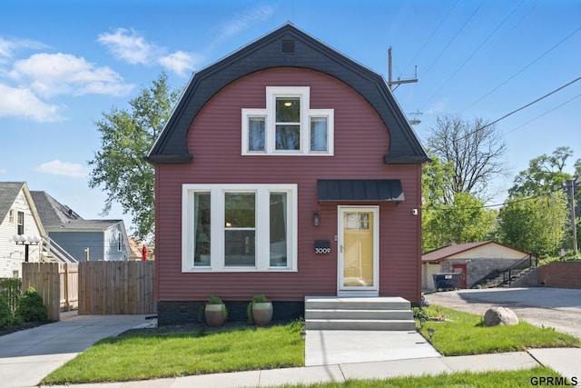 dutch colonial with fence and a gambrel roof