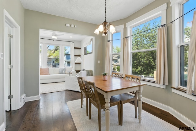 dining area with healthy amount of natural light, baseboards, dark wood-style flooring, and a textured ceiling